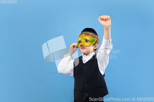 Image of Portrait of a young orthodox jewish boy isolated on blue studio background, meeting the Passover