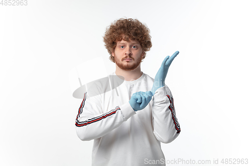 Image of How coronavirus changed our lives. Young man holding thermometer, taking temperature on white background