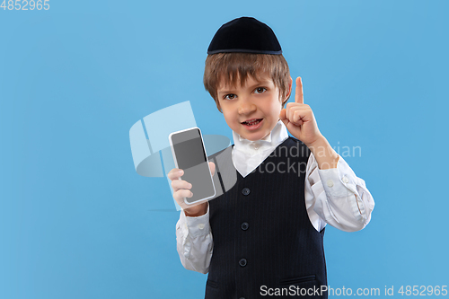 Image of Portrait of a young orthodox jewish boy isolated on blue studio background, meeting the Passover