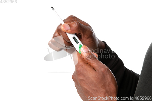 Image of How coronavirus changed our lives. Close up of male hands holding thermometer, taking temperature on white background