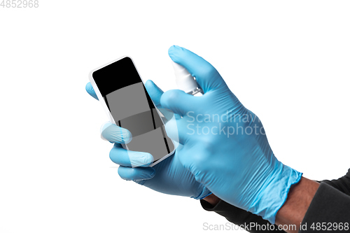 Image of How coronavirus changed our lives. Young man disinfecting gadgets surfaces on white background