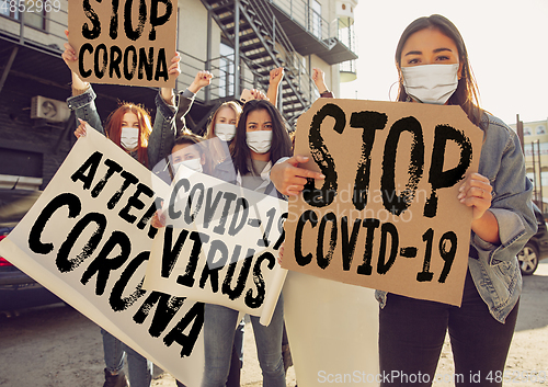 Image of Young people in face masks protesting of stop coronavirus pandemic on the street