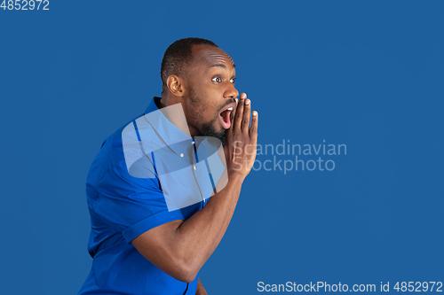 Image of Monochrome portrait of young african-american man on blue studio background