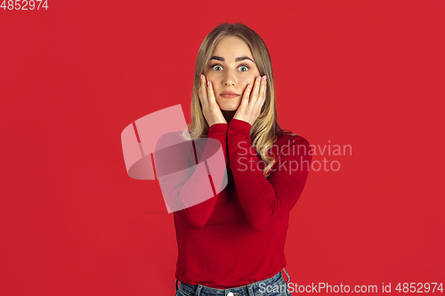 Image of Monochrome portrait of young caucasian blonde woman on red background