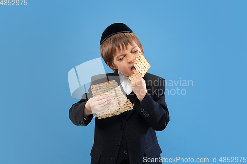 Image of Portrait of a young orthodox jewish boy isolated on blue studio background, meeting the Passover