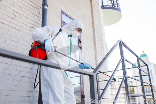 Image of Coronavirus Pandemic. A disinfector in a protective suit and mask sprays disinfectants in the house or office