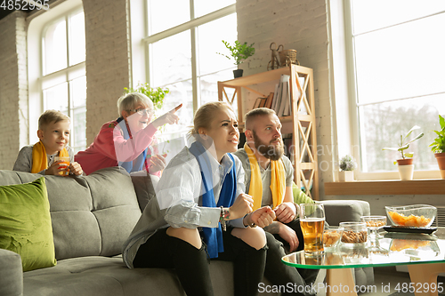 Image of Excited family watching football, sport match at home, top view