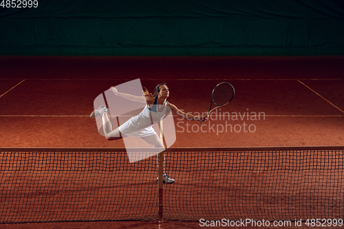 Image of Young caucasian professional sportswoman playing tennis on sport court background