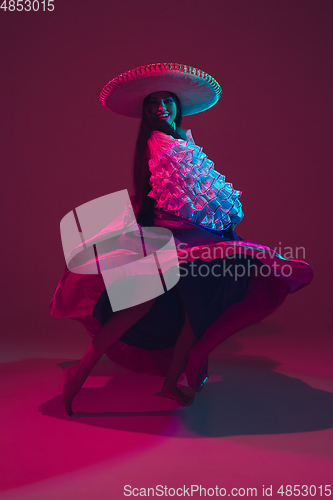 Image of Fabulous Cinco de Mayo female dancer on purple studio background in neon light