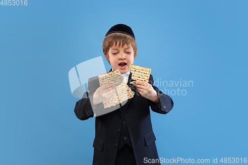 Image of Portrait of a young orthodox jewish boy isolated on blue studio background, meeting the Passover