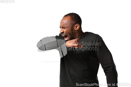 Image of How coronavirus changed our lives. Young man sneezing on white background