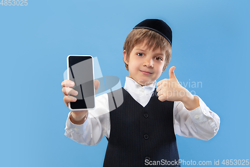 Image of Portrait of a young orthodox jewish boy isolated on blue studio background, meeting the Passover