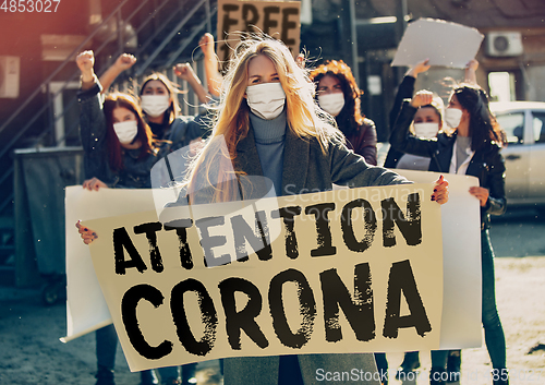Image of Young people in face masks protesting of stop coronavirus pandemic on the street