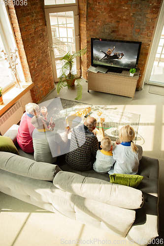 Image of Excited family watching american football, sport match at home