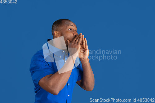 Image of Monochrome portrait of young african-american man on blue studio background