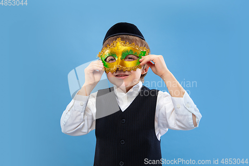 Image of Portrait of a young orthodox jewish boy isolated on blue studio background, meeting the Passover