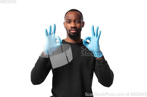 Image of How coronavirus changed our lives. Young man holding thermometer, taking temperature on white background