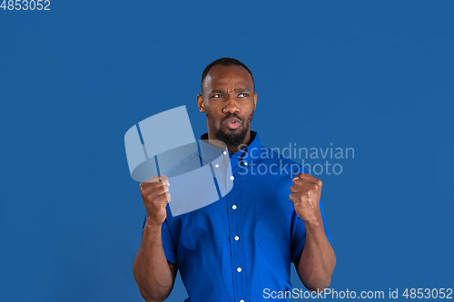 Image of Monochrome portrait of young african-american man on blue studio background
