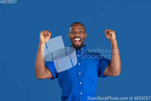 Image of Monochrome portrait of young african-american man on blue studio background