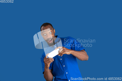 Image of Monochrome portrait of young african-american man on blue studio background