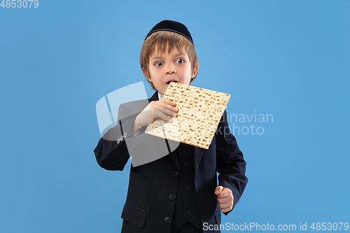 Image of Portrait of a young orthodox jewish boy isolated on blue studio background, meeting the Passover