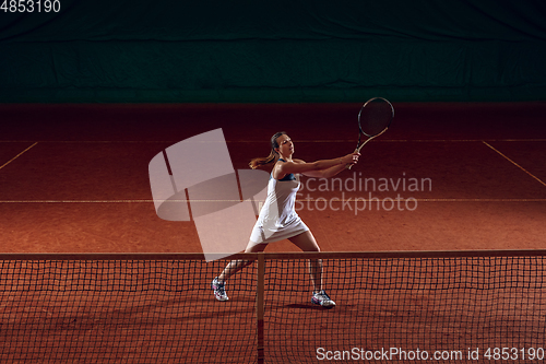 Image of Young caucasian professional sportswoman playing tennis on sport court background