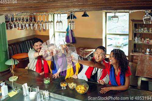 Image of Sport fans cheering at bar, pub and drinking beer while championship, competition is going