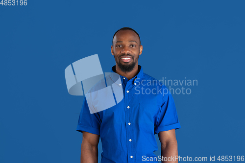Image of Monochrome portrait of young african-american man on blue studio background