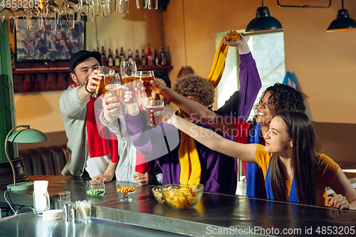 Image of Sport fans cheering at bar, pub and drinking beer while championship, competition is going