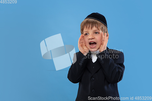 Image of Portrait of a young orthodox jewish boy isolated on blue studio background, meeting the Passover