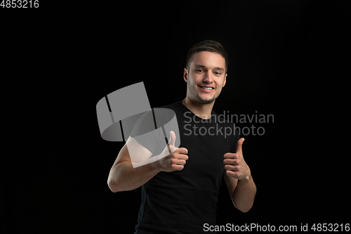 Image of Monochrome portrait of young caucasian man on black studio background