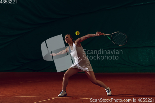 Image of Young caucasian professional sportswoman playing tennis on sport court background