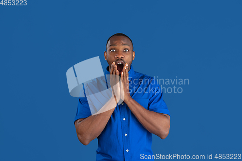 Image of Monochrome portrait of young african-american man on blue studio background