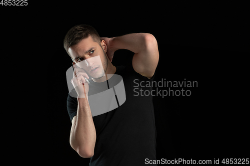 Image of Monochrome portrait of young caucasian man on black studio background