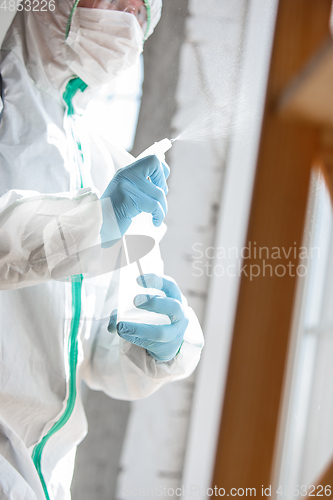 Image of Coronavirus Pandemic. A disinfector in a protective suit and mask sprays disinfectants in the house or office