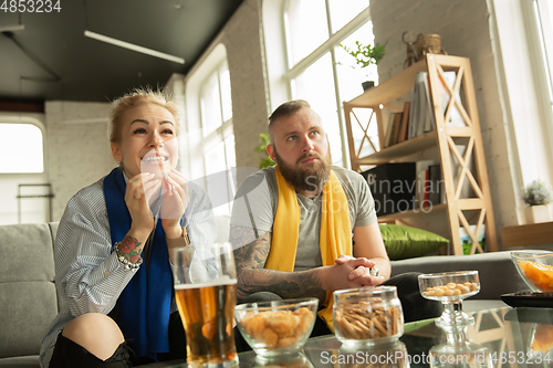 Image of Excited family watching football, sport match at home, beautiful couple