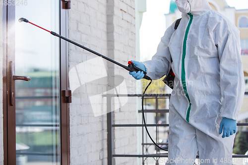 Image of Coronavirus Pandemic. A disinfector in a protective suit and mask sprays disinfectants in the house or office