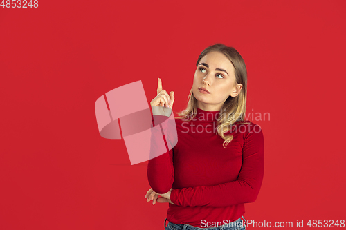 Image of Monochrome portrait of young caucasian blonde woman on red background