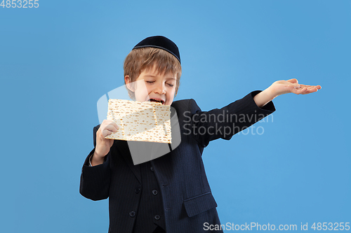 Image of Portrait of a young orthodox jewish boy isolated on blue studio background, meeting the Passover