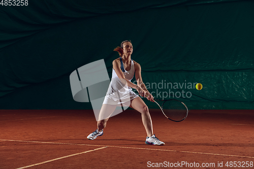 Image of Young caucasian professional sportswoman playing tennis on sport court background