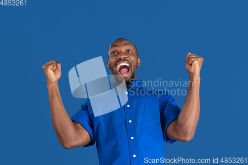 Image of Monochrome portrait of young african-american man on blue studio background
