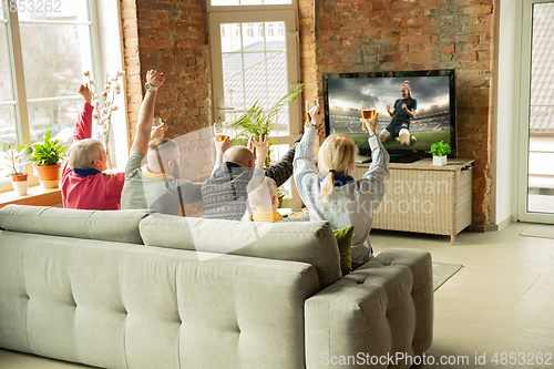 Image of Excited family watching female football, sport match at home