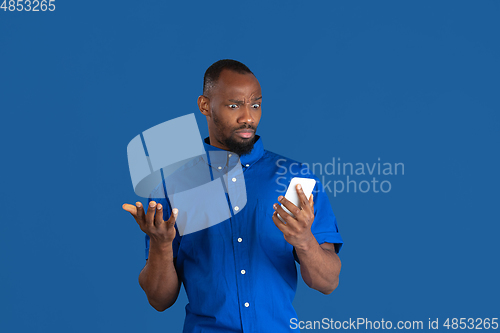 Image of Monochrome portrait of young african-american man on blue studio background