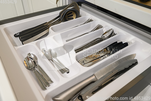 Image of Open drawer with cutlery at modern white woden kitchen in classic style