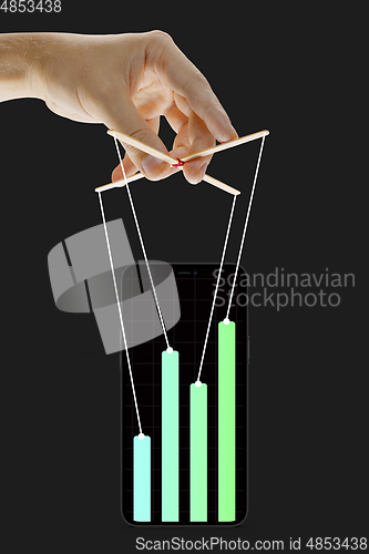 Image of Businessman keeping the growth in economy, manipulating graphs like puppet