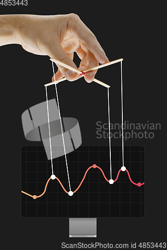 Image of Businessman keeping the growth in economy, manipulating graphs like puppet