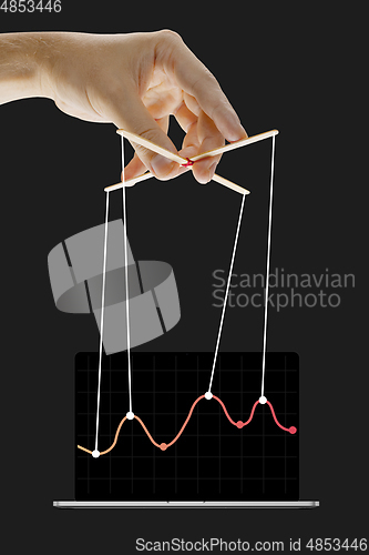 Image of Businessman keeping the growth in economy, manipulating graphs like puppet