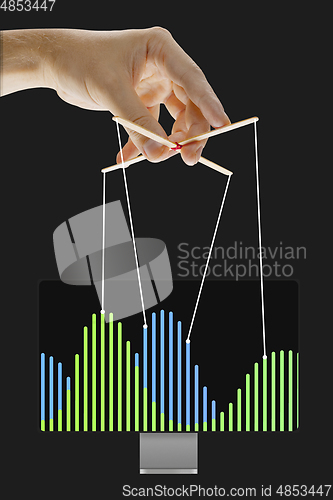 Image of Businessman keeping the growth in economy, manipulating graphs like puppet