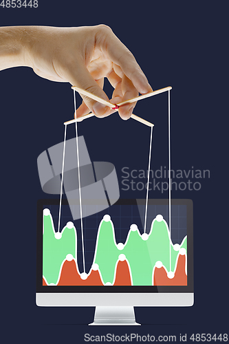 Image of Businessman keeping the growth in economy, manipulating graphs like puppet