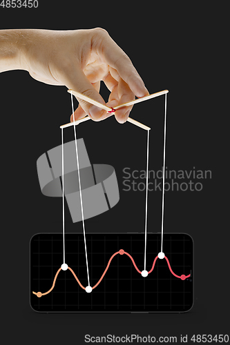 Image of Businessman keeping the growth in economy, manipulating graphs like puppet